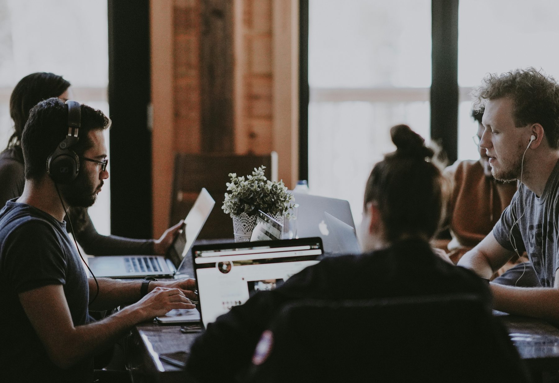 A team working side by side at a shared table, laptops open